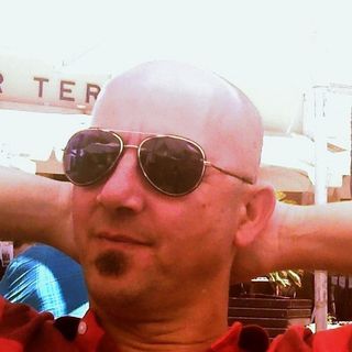 Enrique, con gafas de sol y las manos detrás de la cabeza, sentado en la terraza de un bar.